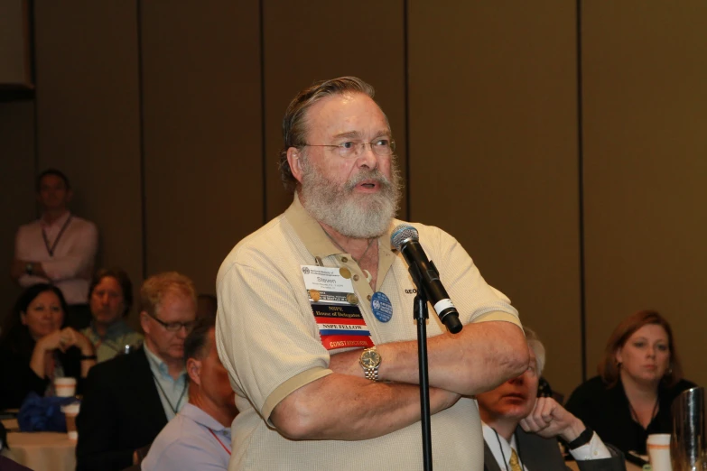 an older man standing at a microphone during a presentation