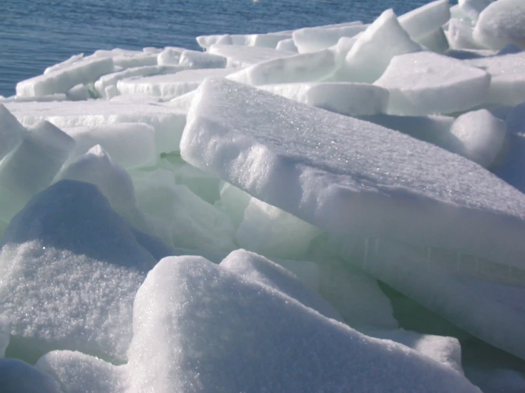 ice formations, close to the water, with a person in the distance walking on one side