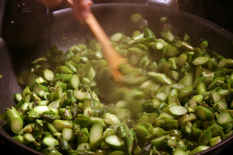 some green vegetables are being cooked in a large pan