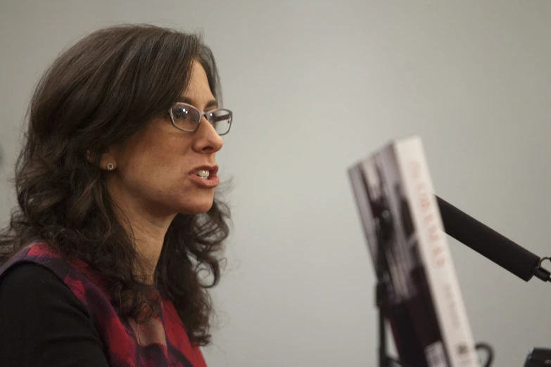 woman in black jacket speaking at a podium