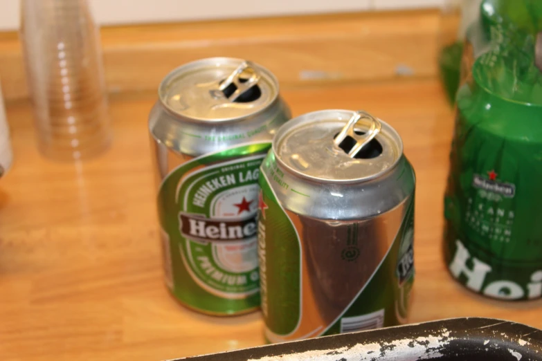 two cans of beer on a table with cans and glasses