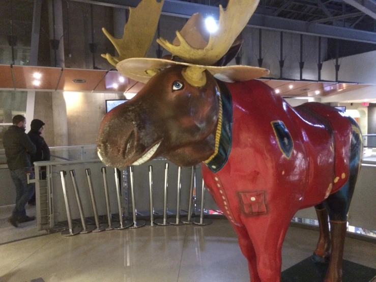 a statue of an animal wearing a red coat with gold antlers