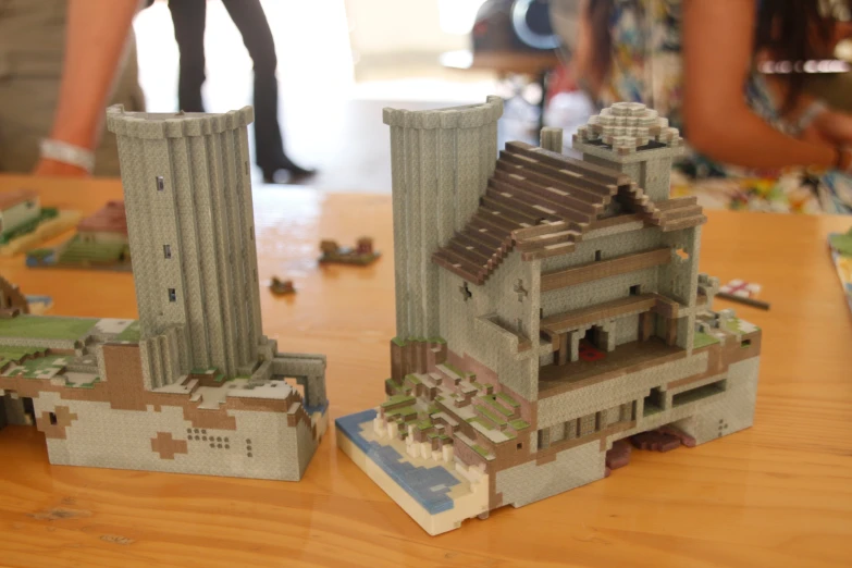 two model buildings are shown on a wooden table