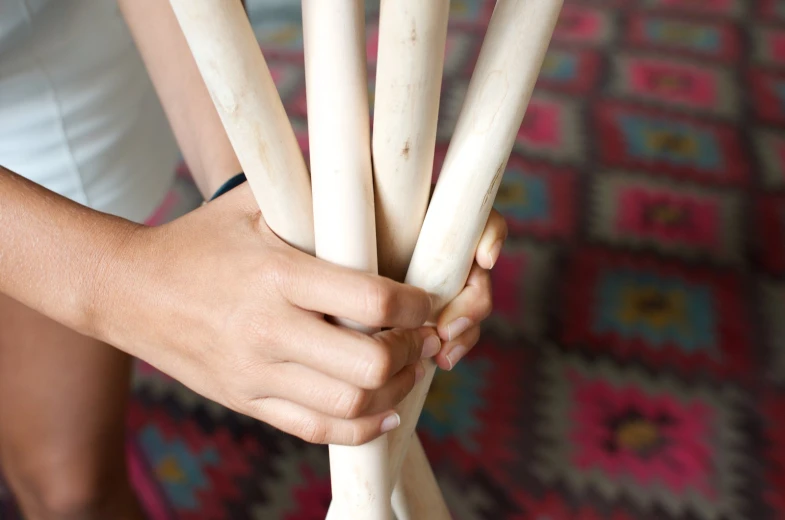 hand holding several wooden sticks over carpet