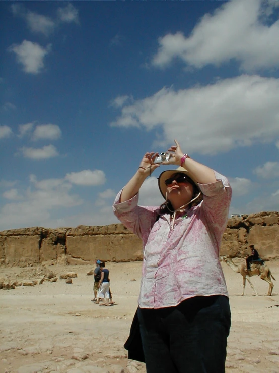 a woman is standing on the sand with her hands on her head