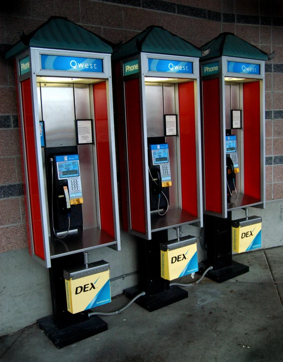 two old fashioned red and black payphones are attached to a wall