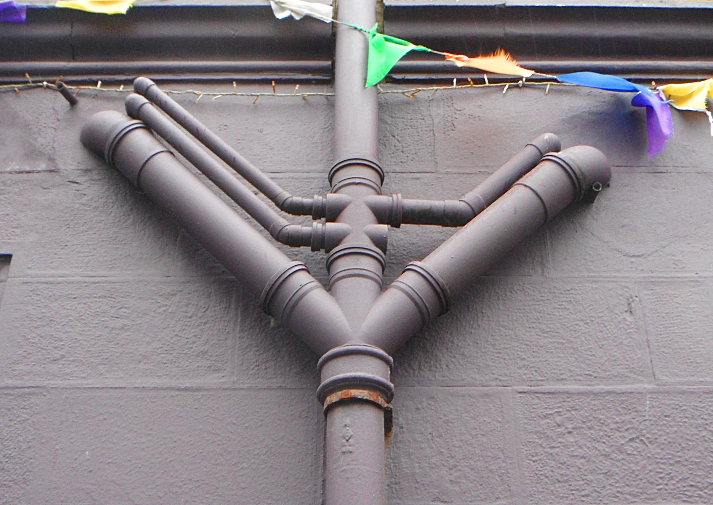 a view from the bottom of a gray pipe with a rainbow kite hanging from it