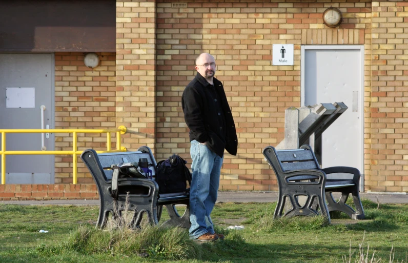 a man standing next to a table and chair in front of a building