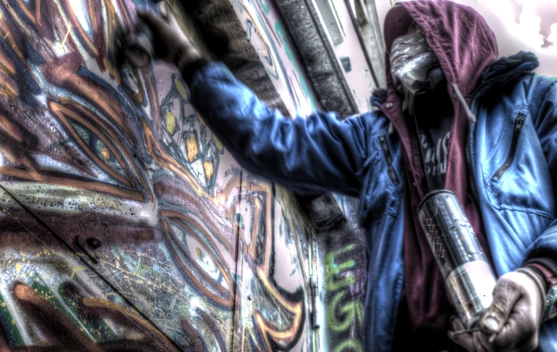 there is a man standing next to a wall with graffiti
