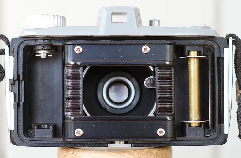 an old fashioned black camera on top of a wooden post