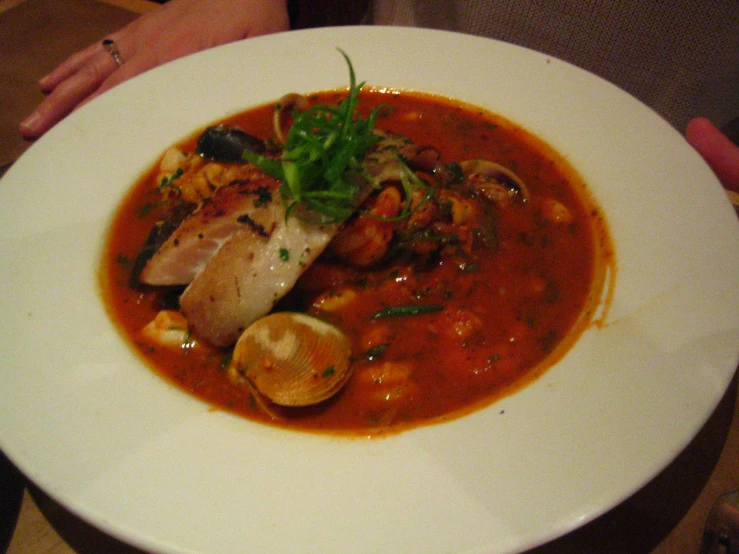 a bowl of stew with some bread, broccoli and other food on a table