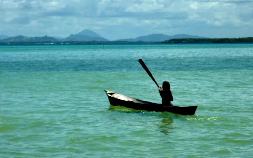 a person paddling a canoe in calm water