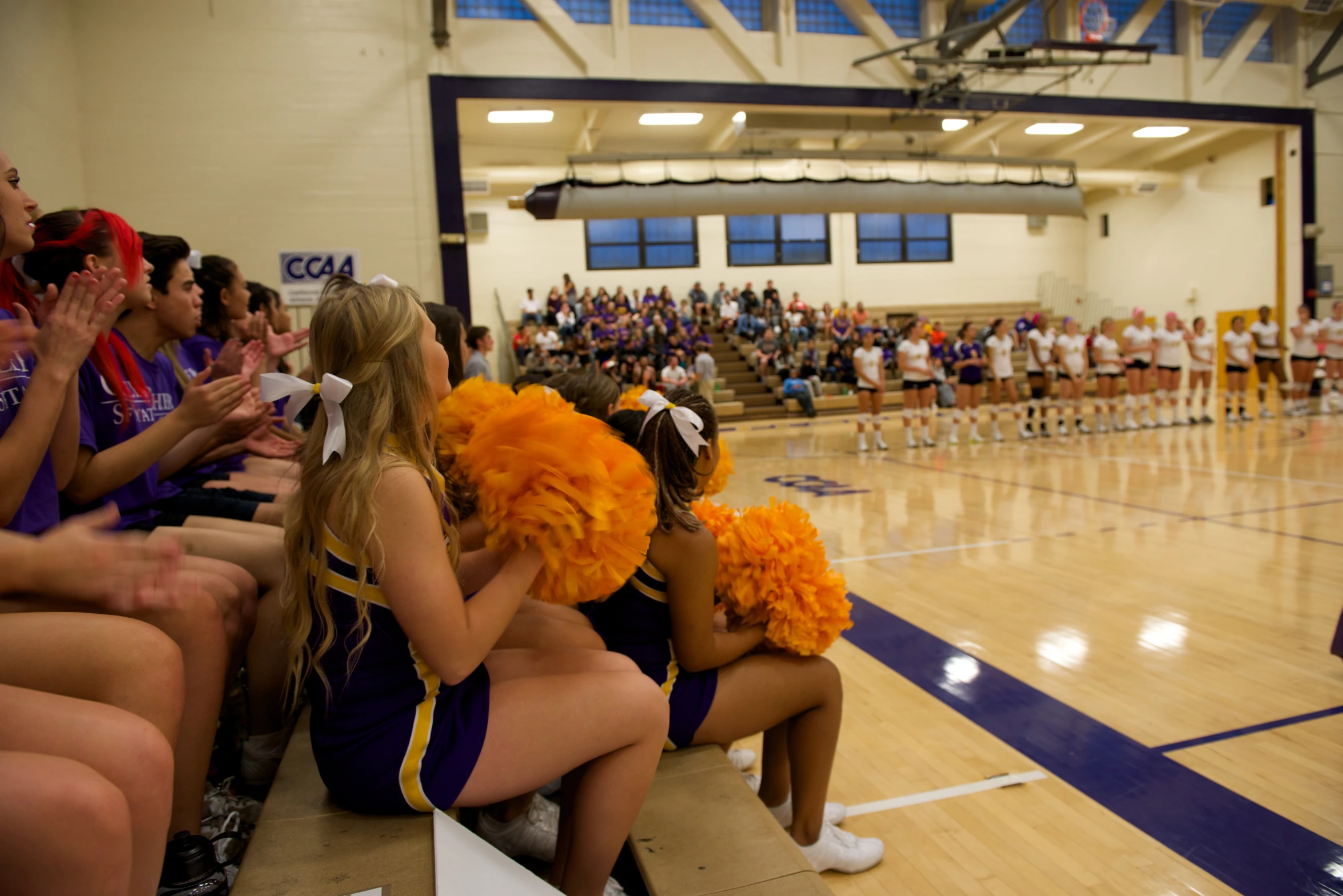 two cheerleaders sitting on bench in a gymnasium