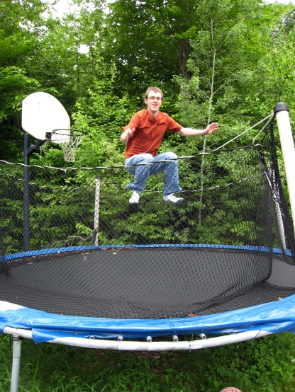 a young man standing on a trampoline on the grass