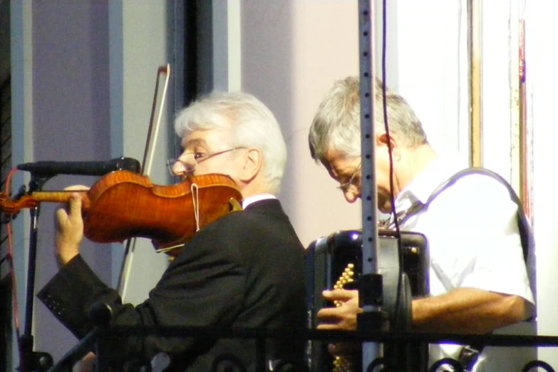 an elderly man playing the violin with an adult woman