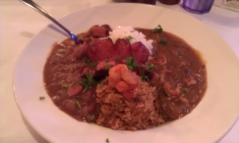 a white bowl with meat, rice and beans on it