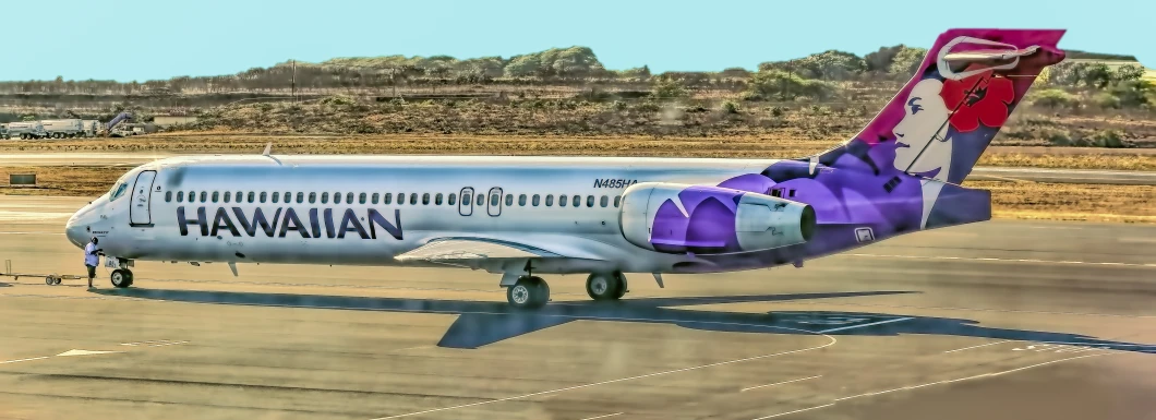 a hawaiian airplane is on the runway in the sun