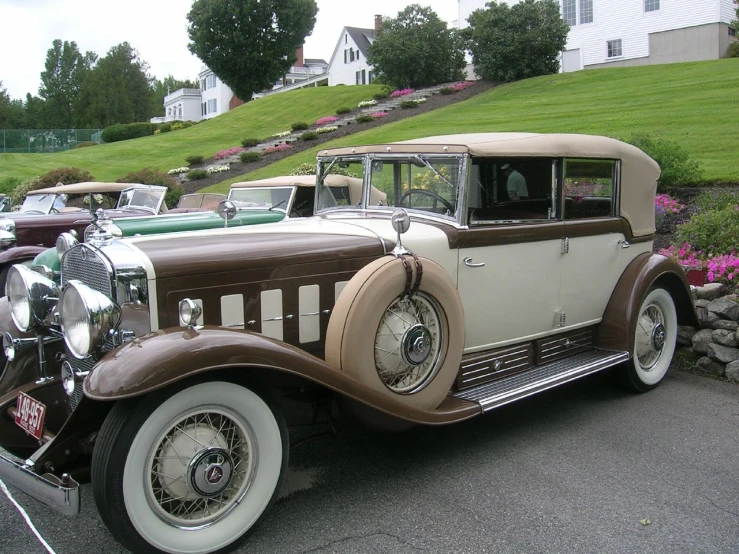 an antique car is parked in a lot next to a hillside