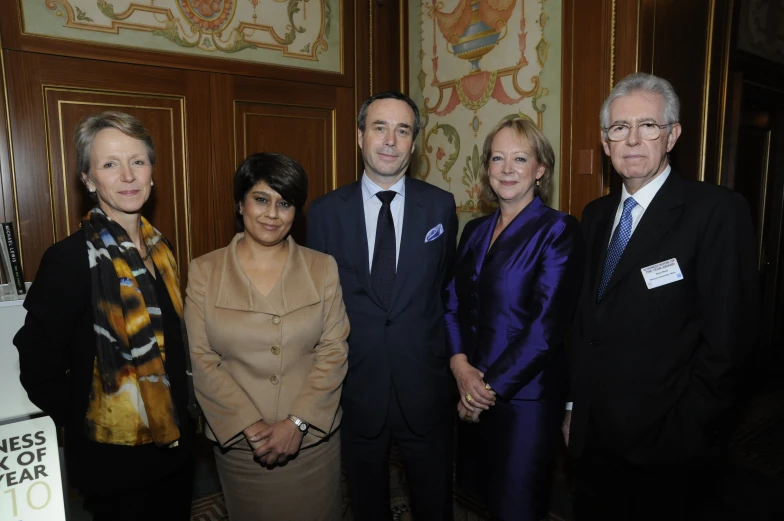 five people standing next to each other in suits