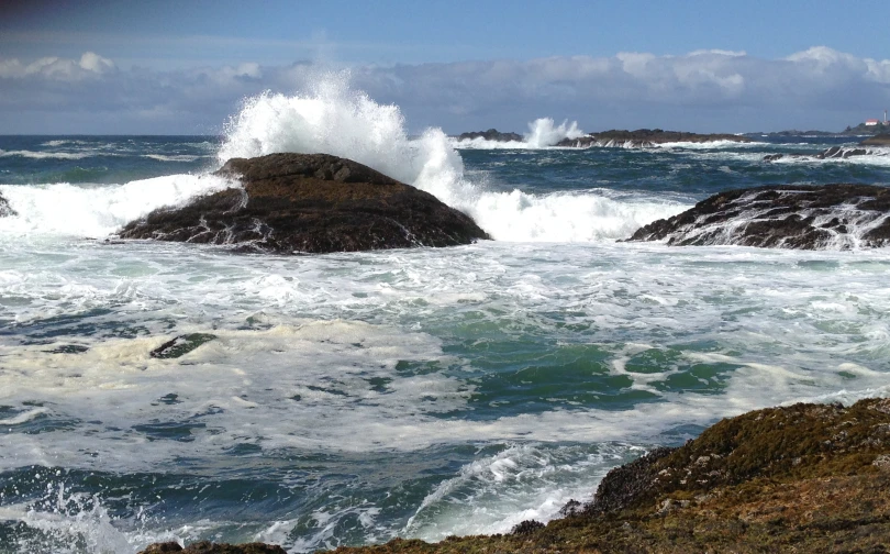 a large wave splashing on the rocks and crashing