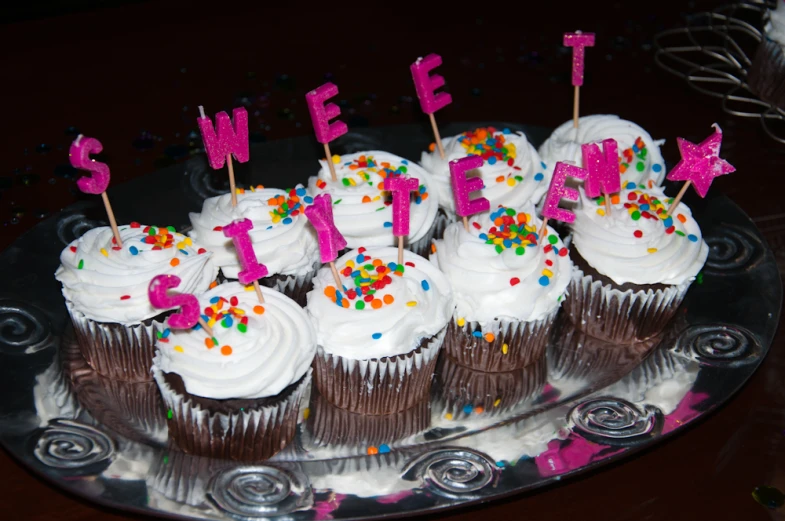 several cupcakes on a plate with name candles