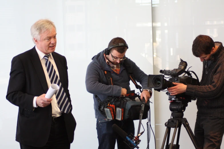 men in suits using camera to video a news shoot