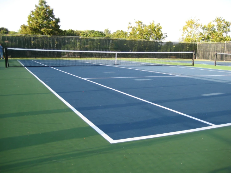 an outdoor tennis court is surrounded by grass