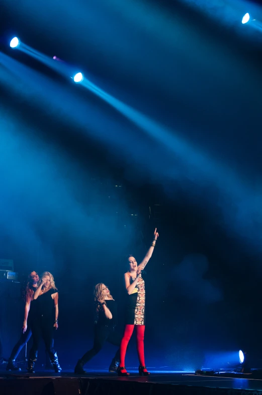 a girl on stage with hands up in the air