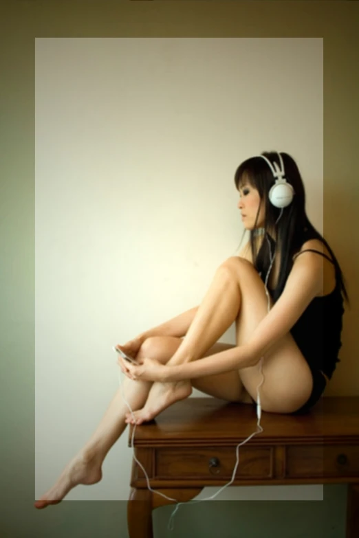 woman in headphones sitting on a desk with leg in a tight, short dress