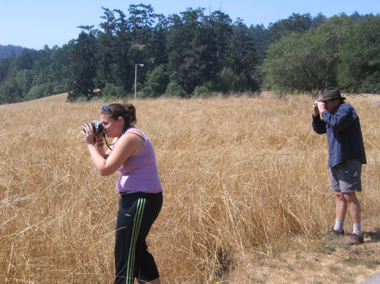 a man and a woman are taking pictures in a field