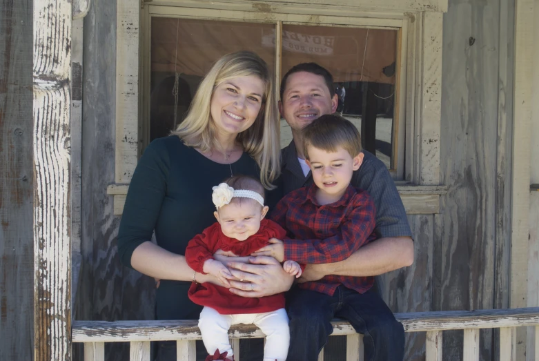 a woman holding a child sitting next to two men