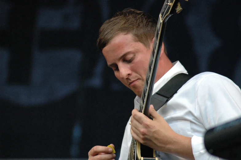 a male in a white shirt and black guitar