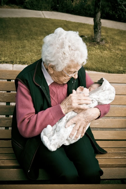 an elderly woman is sitting on a bench holding a kitten