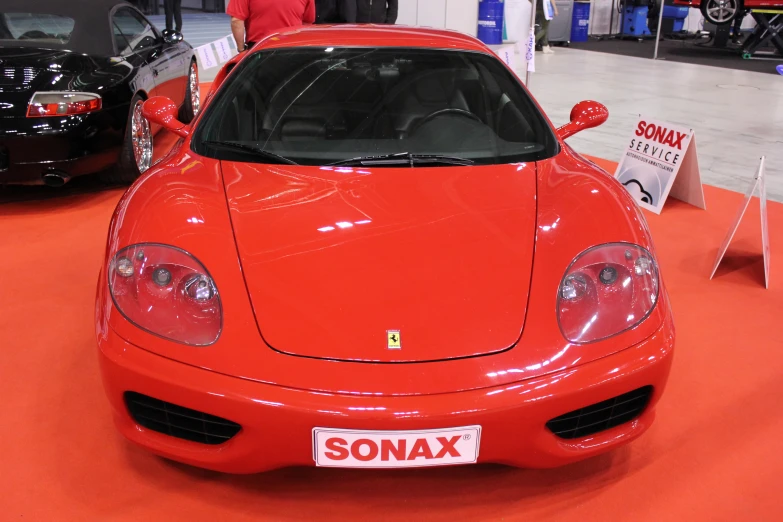 the red sports car is being displayed at the show