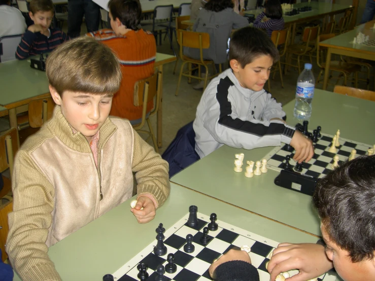 boys are sitting at a table playing chess