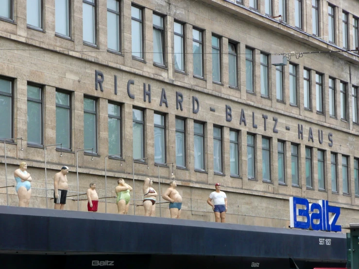 some bodysuit clad mannequins stand on a building wall