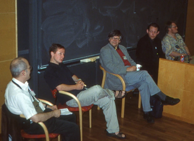 a group of men sitting in chairs talking