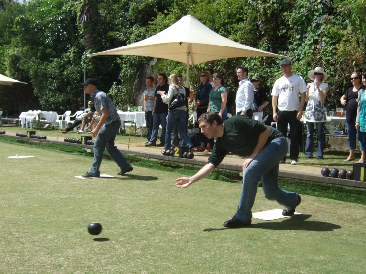 several men in front of an outdoor bowling match