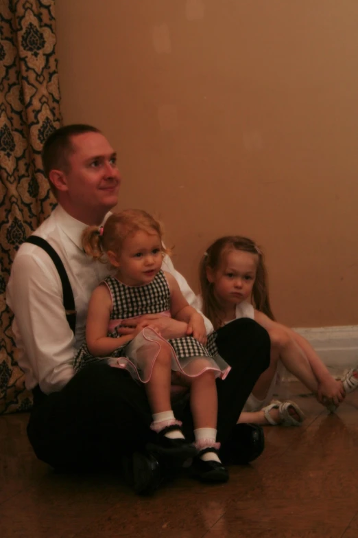 a man is holding two children while they are posing