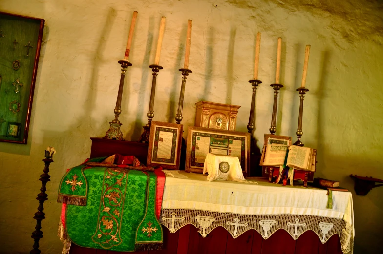 a table filled with pictures and candles and a painting on the wall