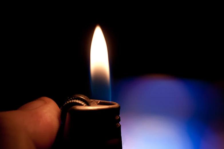 a lit lighter sitting in the dark with blue light behind it