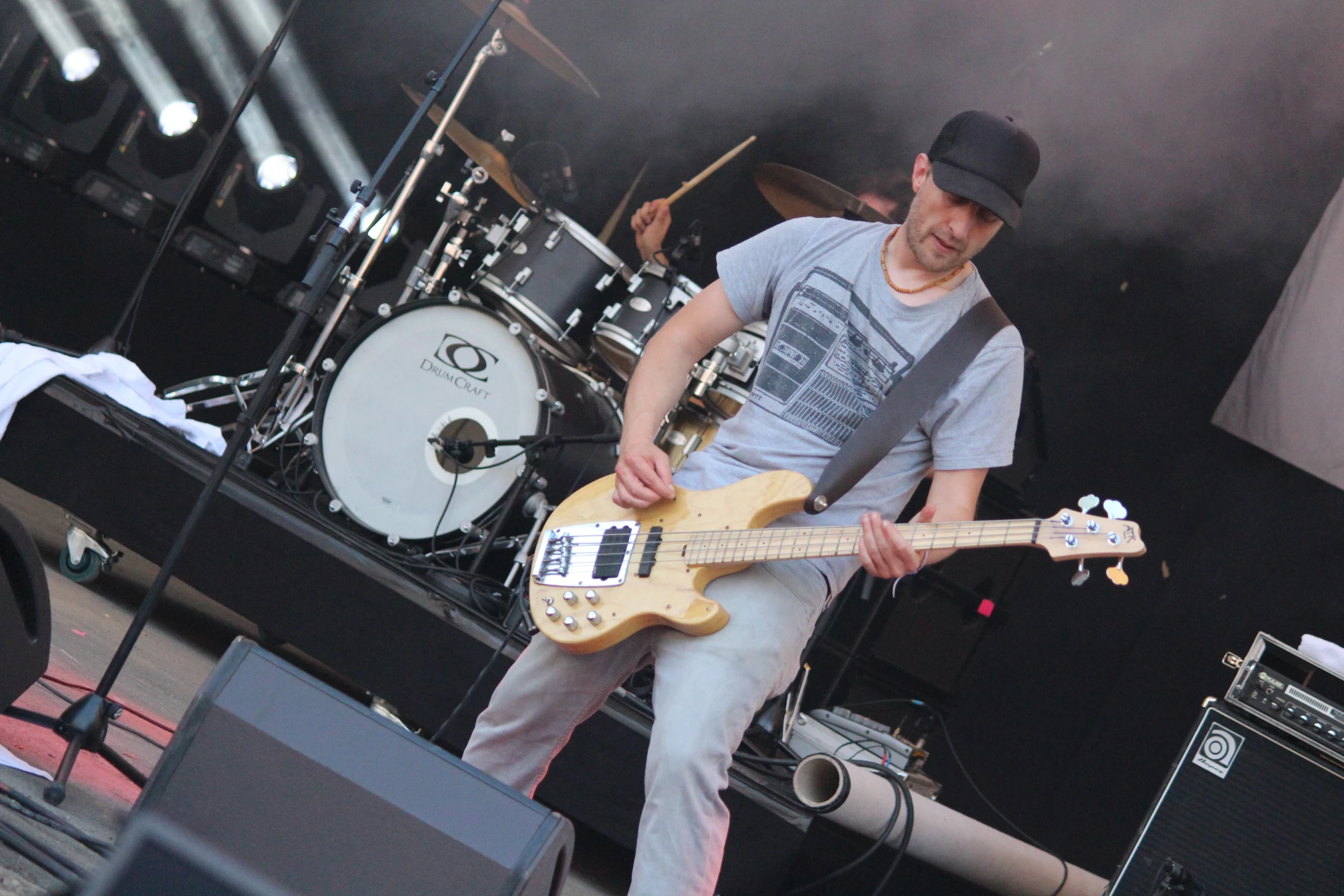 a male with a black hat is playing his guitar