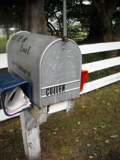 mail box and mail envelope on wooden post near white fence