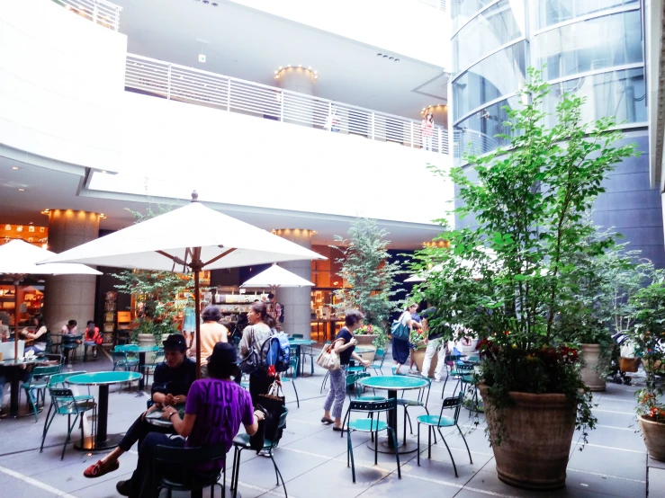 people sit at tables in an indoor plaza