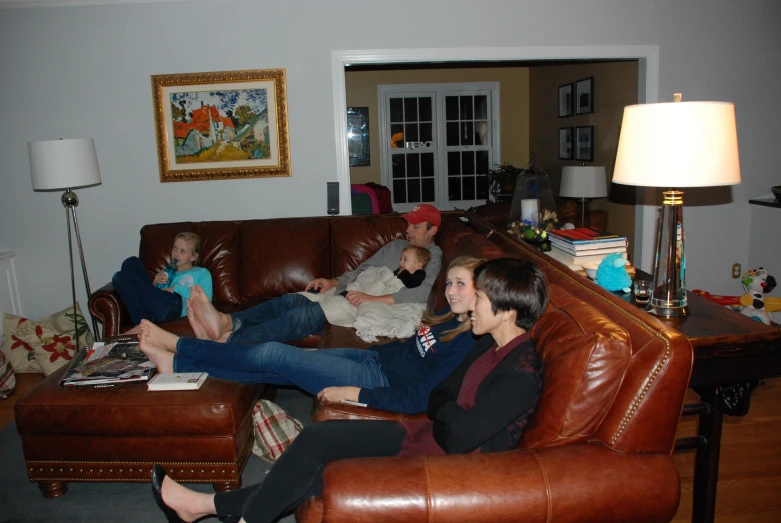 people are sitting on a couch with children in the living room