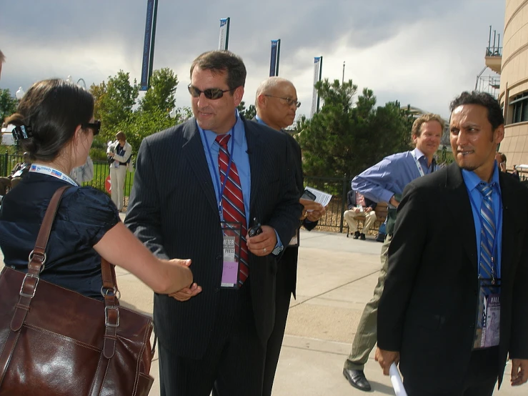 a group of men in business attire standing in front of a building