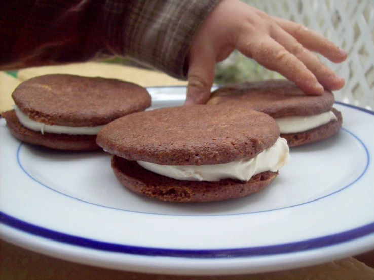 three biscuits with cream filling on a plate