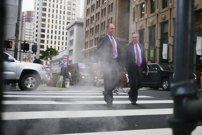 two men walk across a street in a city