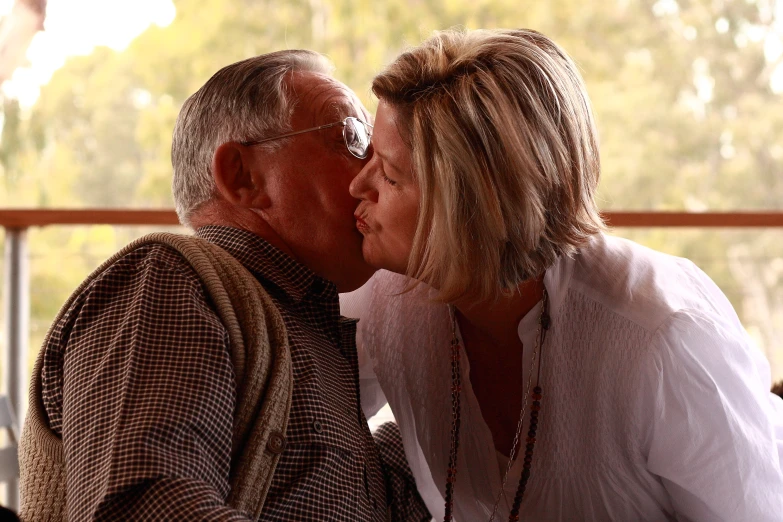 an older couple kissing each other on a deck