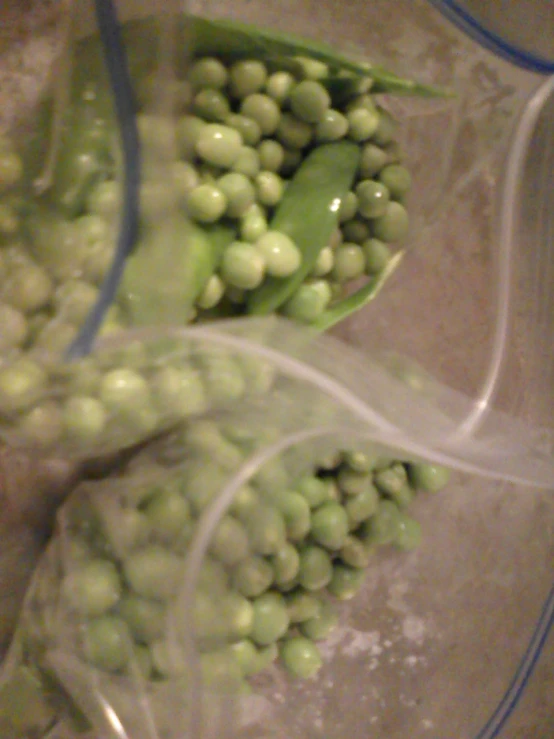 peas and pea pods in plastic wrapping on tile floor